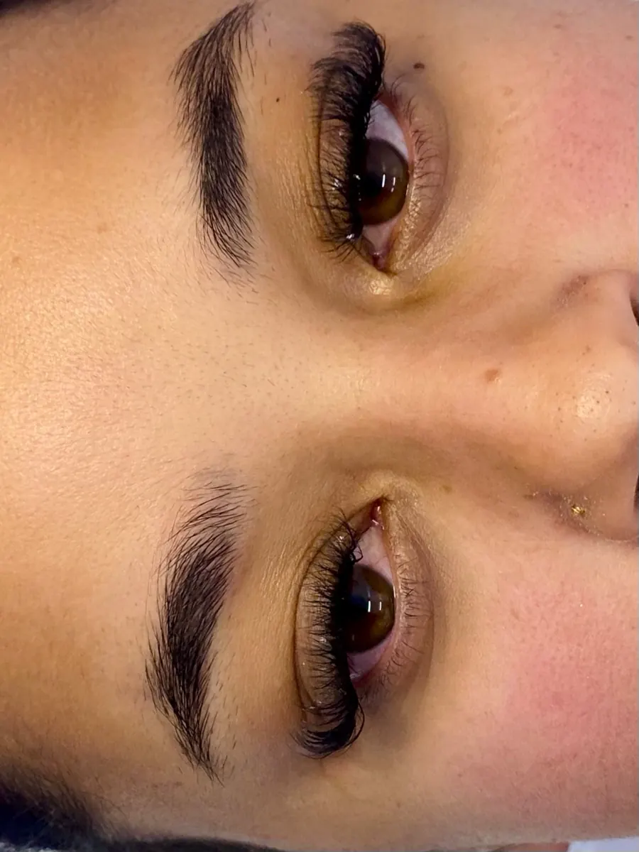 Os dois olhos de uma cliente com cílios alongados e sobrancelhas em destaque.